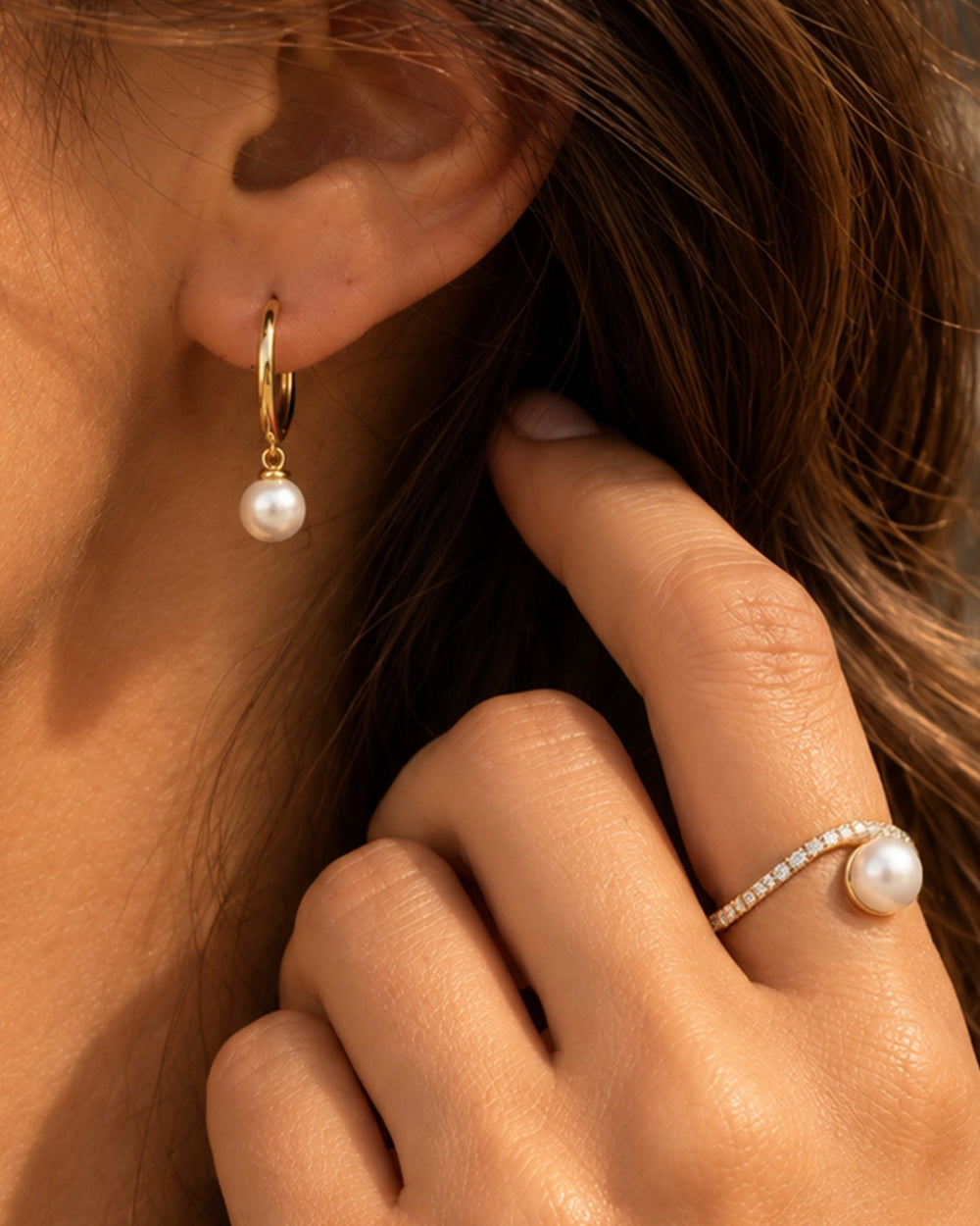 Model wearing a gold-tone freshwater pearl drop earring and pearl ring