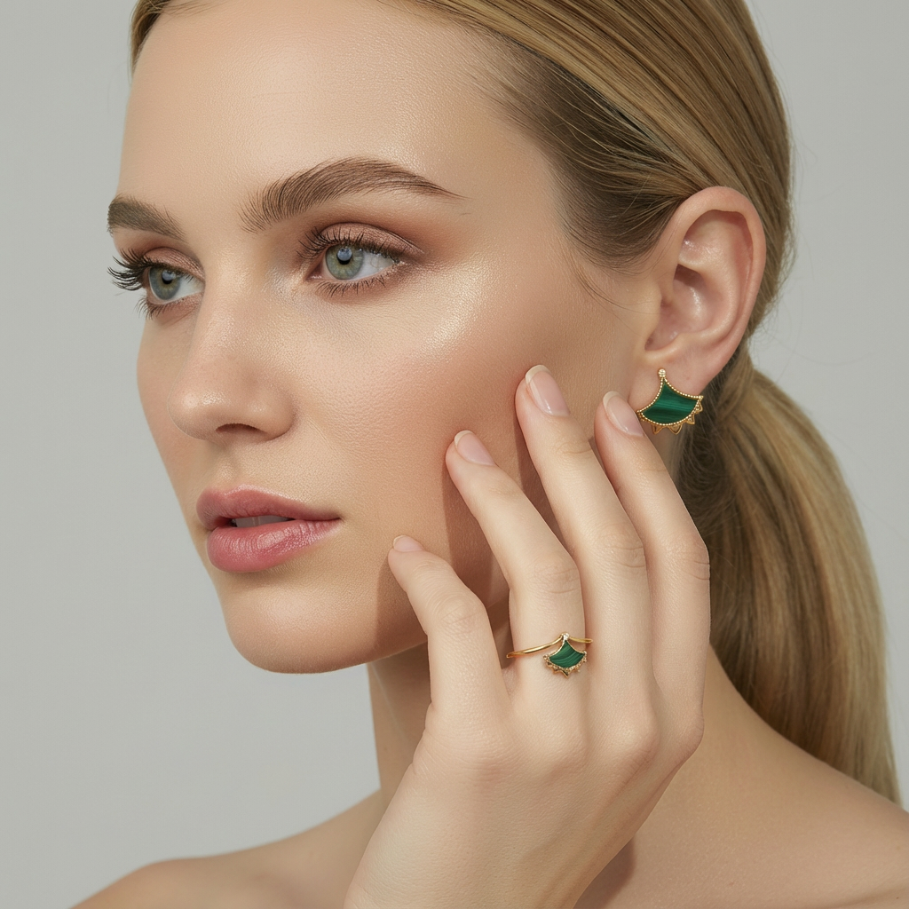 Close-up of a woman wearing Malachite earrings and ring, with a neutral background.