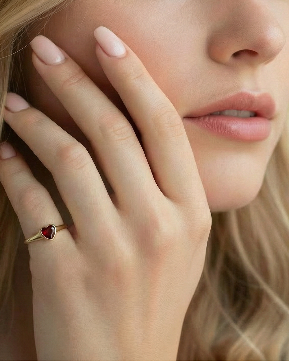 Close-up of a model wearing a heart-shaped red garnet ring