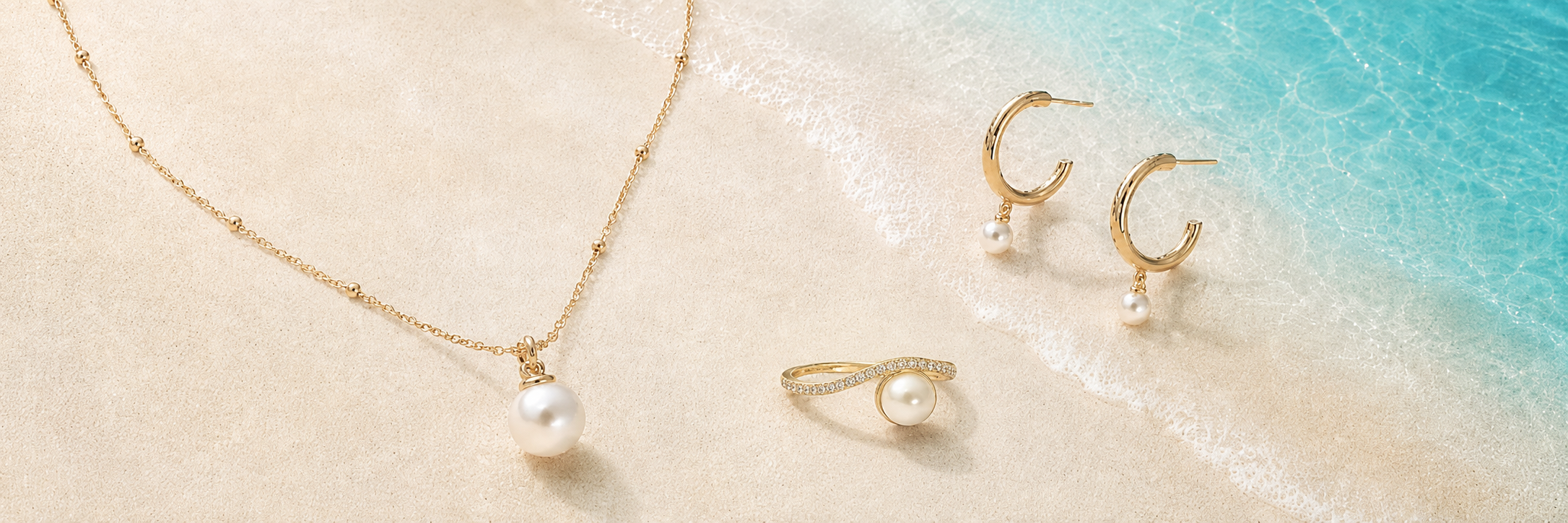 Tempo Solo Freshwater Pearl Necklace, Orbit Freshwater Pearl Hoop Earrings and Embrace Freshwater Pearl Ring in 18kt gold vermeil on a coastal shoreline | Cirque D'Or